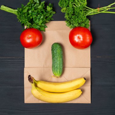 Sebzeli komik surat ve ahşap arka planda meyveler. Geri dönüştürülebilir ekolojik paketler kavramı. durgun hayat