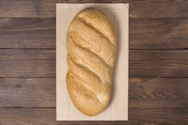 classic loaf in a steam package that is made of recycled material on a wooden background, paper bag concept