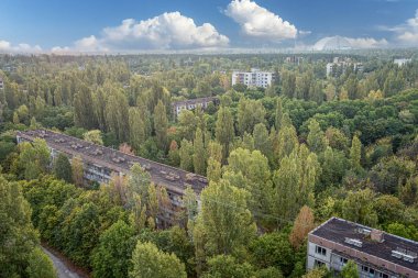 Kayıp şehir Pripyat 'ın hava manzarası mavi gökyüzü ve bulutlar. Ağaçlarla kaplı bir sürü boş beton zemin. Pripyat, Çernobil nükleer santralindeki kazadan sonra 33 yıl boyunca boşaldı.