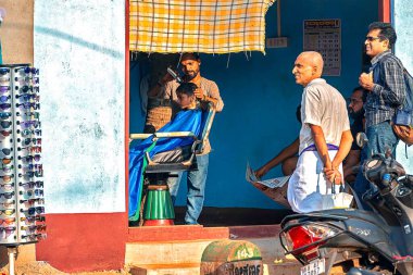 12 / 27 / 2019 Gokarna. Karnataka, Hindistan, bir adam berber dükkanında genç bir Hintliye saç kesimi yapıyor.