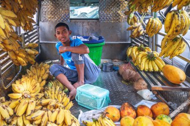 01 / 22 / 2020 Myanmar (Burma) Yangon, Birmanya pazarında olgun muz satan genç bir Burmalı. Bölgenin dört bir yanından insanların ürün satmak ve satın almak için geldiği yerel bir pazar..