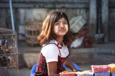 01 / 21 / 2020 Yangon, Myanmar. Birmanyalı genç kız geleneksel tanaka ile sıvanmış Yangon caddesinde güvercin maması satıyor. Yoksulluk ve cömertlik kavramı