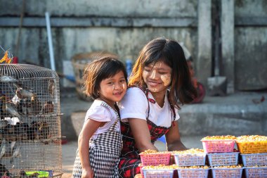 01 / 21 / 2020 Yangon, Myanmar. Birmanyalı genç kız geleneksel tanaka ile sıvanmış Yangon caddesinde güvercin maması satıyor. Yoksulluk ve cömertlik kavramı