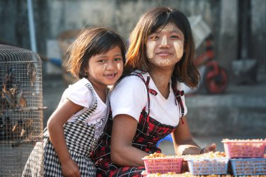01 / 21 / 2020 Yangon, Myanmar. Birmanyalı genç kız geleneksel tanaka ile sıvanmış Yangon caddesinde güvercin maması satıyor. Yoksulluk ve cömertlik kavramı