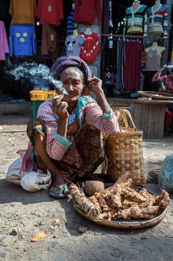21 / 01 / 2020 Bagan, Myanmar. Yaşlı buruşuk Asyalı kadın markette geleneksel puro içiyor.