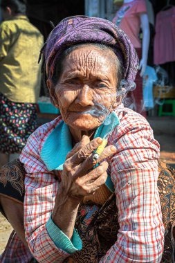 21 / 01 / 2020 Bagan, Myanmar. Yaşlı buruşuk Asyalı kadın markette geleneksel puro içiyor.