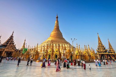 01 / 21 / 2020 Myanmar, Yangon, Altın Pagoda Mavi gökyüzüne karşı Shwedagon ve pek çok kişi dua ediyor. Shwedagon Pagoda, Myanmar 'daki en kutsal Budist tapınağıdır.