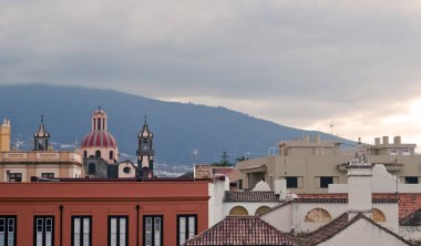 View of the Villa de la Orotava in Tenerife, are their homes and roofs, a church and mountains with at the background  clipart