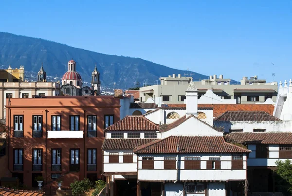 View of the Villa de la Orotava in Tenerife, are their homes and roofs, a church and mountains with at the background