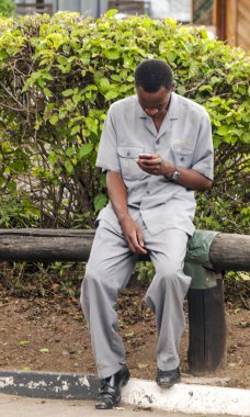 Masai Mara Kenya - Mayıs 2014. Yerli Afrika kökenli Amerikalı adam cep telefonu ile net sörf
