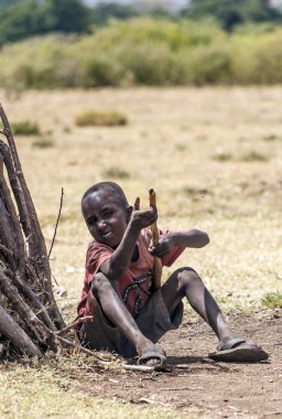 Masai Mara, Kenya - Mayıs 201: Küçük tanımlanamayan Kenya çocuk Masai kabilesinden Masai Mara, Kenya ünlü Ulusal Rezerv parklarından biri olan basit ve kirli kıyafetlerle ile giyinmiş