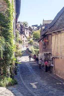 Conques, Aveyron, Fransa - Eylül 2014. Anonim insanlar güneşli bir günde Conques ortaçağ köyü sokaklarında yürüyüş.