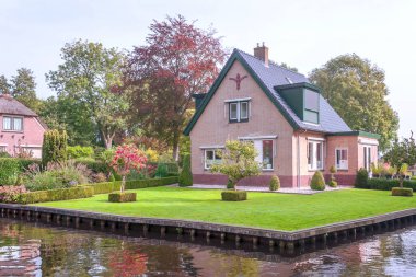 Giethoorn, bulutlu bir günde kanalları ve kırsal evleri olan Hollanda köyü.