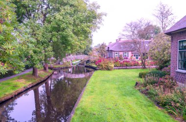 Giethoorn, bulutlu bir günde kanalları ve kırsal evleri olan Hollanda köyü.