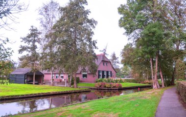 Giethoorn, bulutlu bir günde kanalları ve kırsal evleri olan Hollanda köyü.