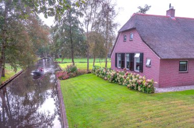 Giethoorn, bulutlu bir günde kanalları ve kırsal evleri olan Hollanda köyü.