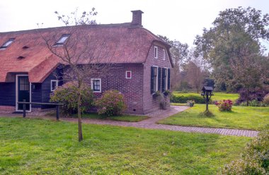 Giethoorn, bulutlu bir günde kanalları ve kırsal evleri olan Hollanda köyü.