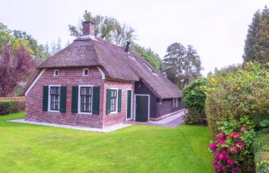 Giethoorn, bulutlu bir günde kanalları ve kırsal evleri olan Hollanda köyü.