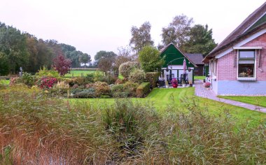 Giethoorn, bulutlu bir günde kanalları ve kırsal evleri olan Hollanda köyü.