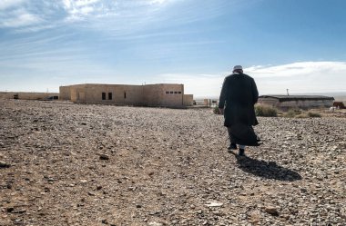 WADI RUM, JORDAN-FEBRUARY 2015. Solitary Arab man walking through the desert. clipart