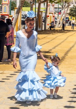SEVILLA, ANDALUSIA, SPAIN-JULY 2015. Anonymous people dressed in flamenco at the Seville fair in Spain on a sunny day clipart