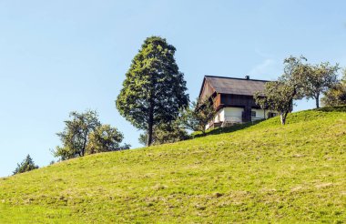 Güneşli bir günde Fransız Alpleri'nde bir tepe üzerinde bulunan yazlık.