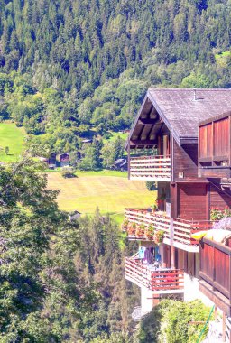 Güneşli bir günde Saint Luc Vadisi'nde İsviçre Alpleri çayırlığında ahşap evler.