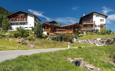 Güneşli bir günde Saint Luc Vadisi'nde İsviçre Alpleri çayırlığında ahşap evler.