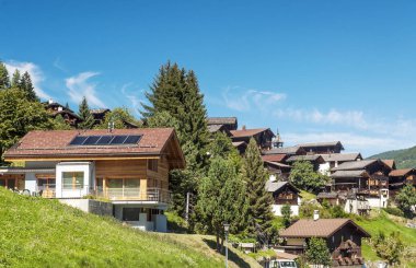 Güneşli bir günde Saint Luc Vadisi'nde İsviçre Alpleri çayırlığında ahşap evler.