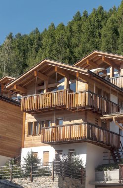 Güneşli bir günde Saint Luc Vadisi'nde İsviçre Alpleri çayırlığında ahşap evler.