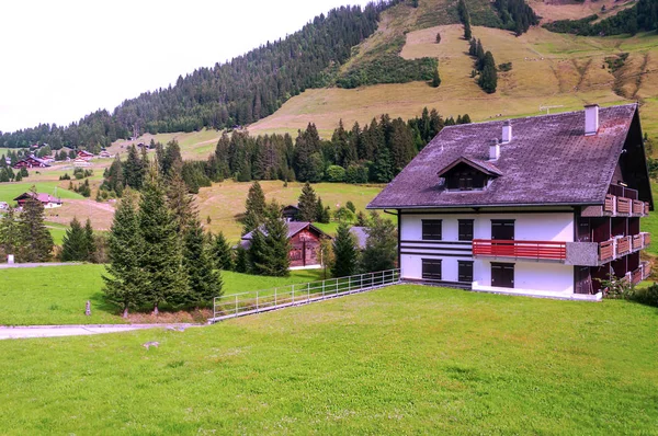木製の小屋と晴れた日に牧草地スイスのアルプスの山々 — ストック写真