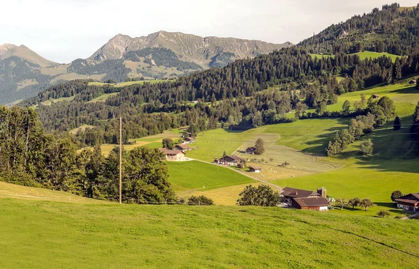 木製の小屋と晴れた日に牧草地スイスのアルプスの山々 — ストック写真