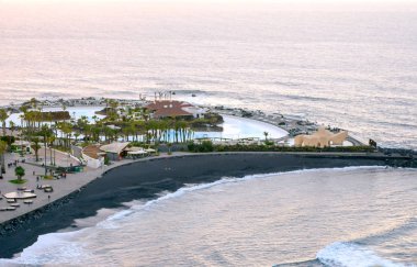 Puerto De La Cruz, Kanarya Adaları, İspanya. Anonim turistler bir palmiye ağacı içinde yürüyüş Puerto de la Cruz güneşli bir günde gezi. Onun bir turistik köy deniz kenarında.