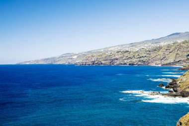 Tenerife, Kanarya Adaları güneşli bir günde kayalarda boyunca kırma dalgalar.