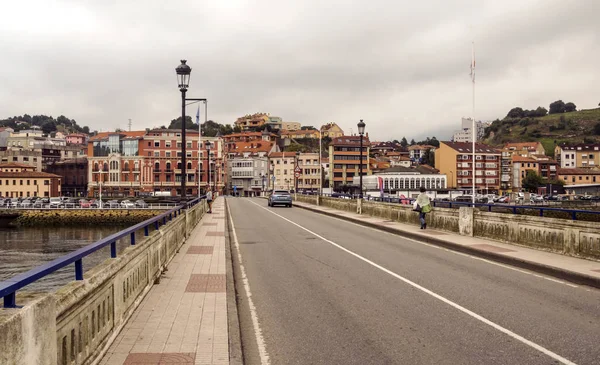 San Vicente de la Barquera, İspanya-Eylül 2018. Sahilde tekne ve bulutlu bir günde sokakta yürüyen insanlar ile denize yakın İspanyol şehir.