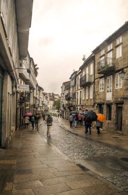 Santiago de Compostela, İspanya-Octuber 2019. Yağmur yağan bir günde şehrin sokağında yürüyen insanlar..