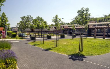 Balatonlelle, Macaristan-Haziran 2019. Güneşli bir günde doğa ile çevrili kasabanın gölü yakınında bir yaz günü sokakta Tren istasyonu.