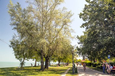 Balatonlelle, Macaristan-Haziran 2019. Güneşli bir günde şehrin gölü yakınında bir yaz günü çim turist.