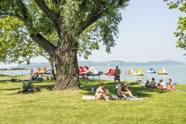 Balatonlelle, Macaristan-Haziran 2019. Güneşli bir günde şehrin gölü yakınında bir yaz günü çim turist.