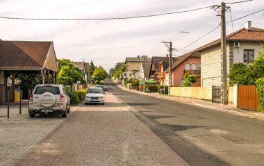Balatonlelle, Macaristan-Haziran 2019. Güneşli bir günde köyde evleri ile çayırlarda Macar kasabasının Yolu.