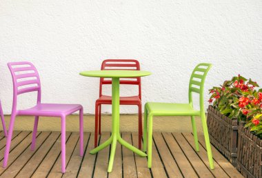 Dört renkli sandalye ve beyaz duvarın yanında bir masa