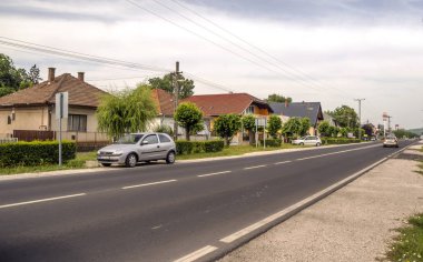 Balatonlelle, Macaristan-Haziran 2019. Güneşli bir günde köyde evleri ile çayırlarda Macar kasabasının Yolu.