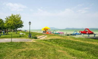 Balatonlelle, Macaristan-Haziran 2019. Güneşli bir günde şehrin gölü yakınında bir yaz günü çim turist.