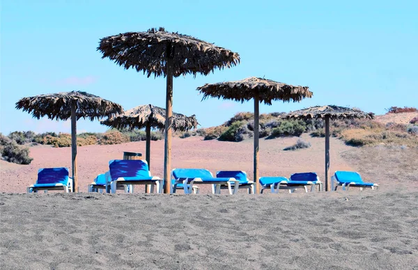 Varios sombrillas y hamacas en la arena de la playa —  Fotos de Stock