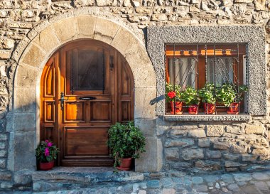 Pencerelerde çiçeklerle süslenmiş antik bir evin cephesi