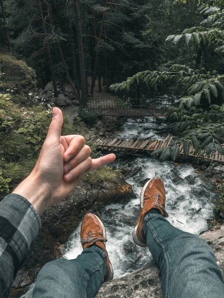 bir şelale üzerinde bir uçurumun kenarına oturdu