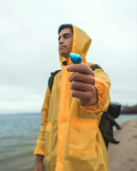 Bir genç yolcusu adam sarı yağmurluk içinde mavi bir taş buldum