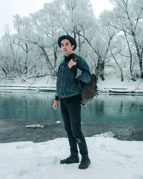 Genç yolcusu adam bir karlı manzara ve masmavi bir deniz arka plan üzerinde şapkalı