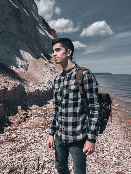 Genç yolcusu adam kayalık sahil boyunca yürür