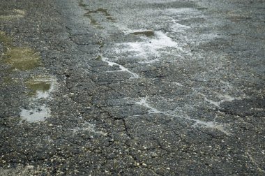 kırık asfalt yolda su birikintileri